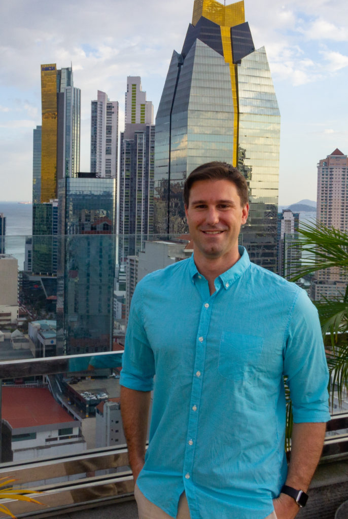 John standing outside with skyscrapers behind him.